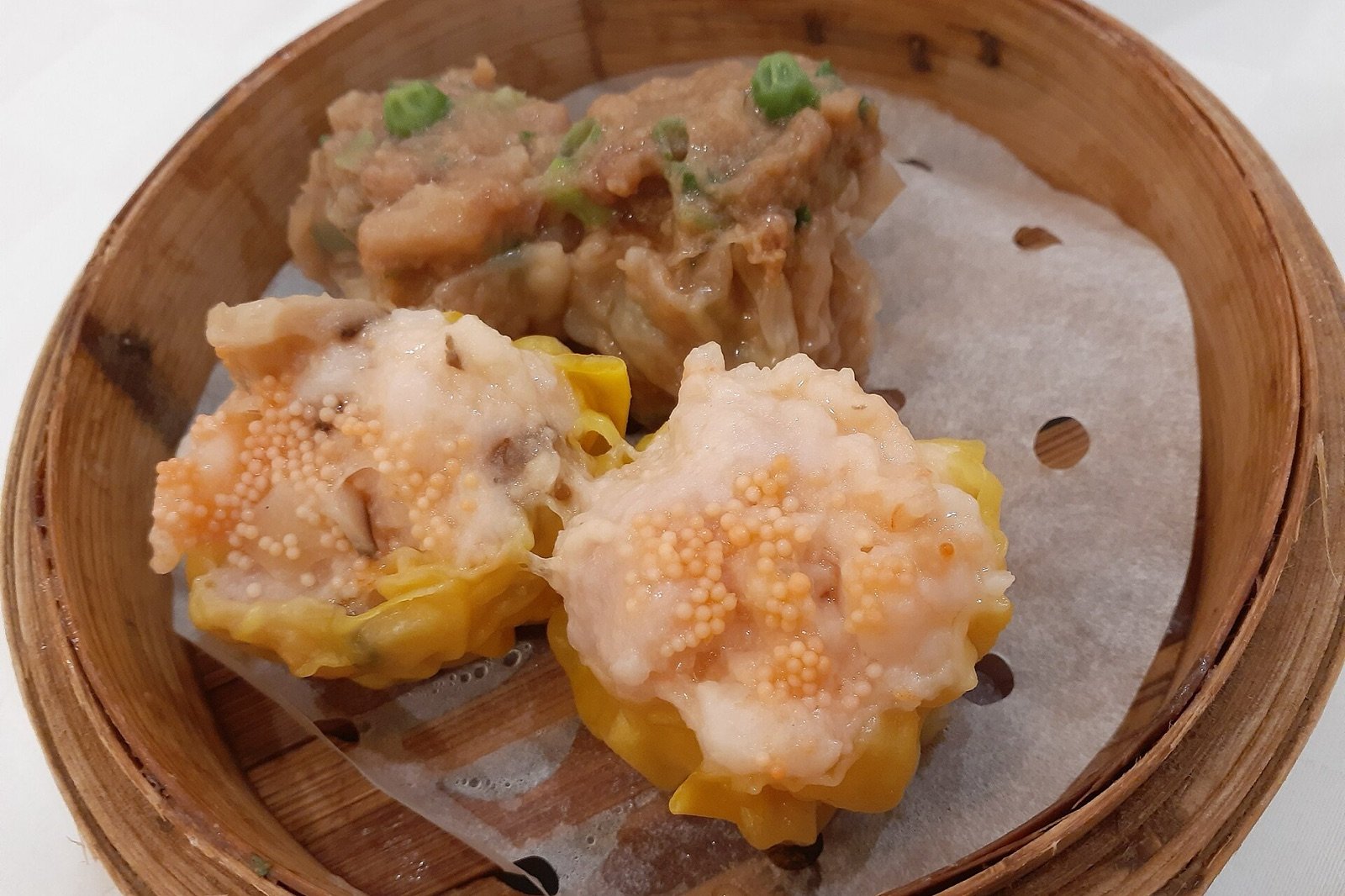 Siu mai dim sum served in a round bamboo steamer
