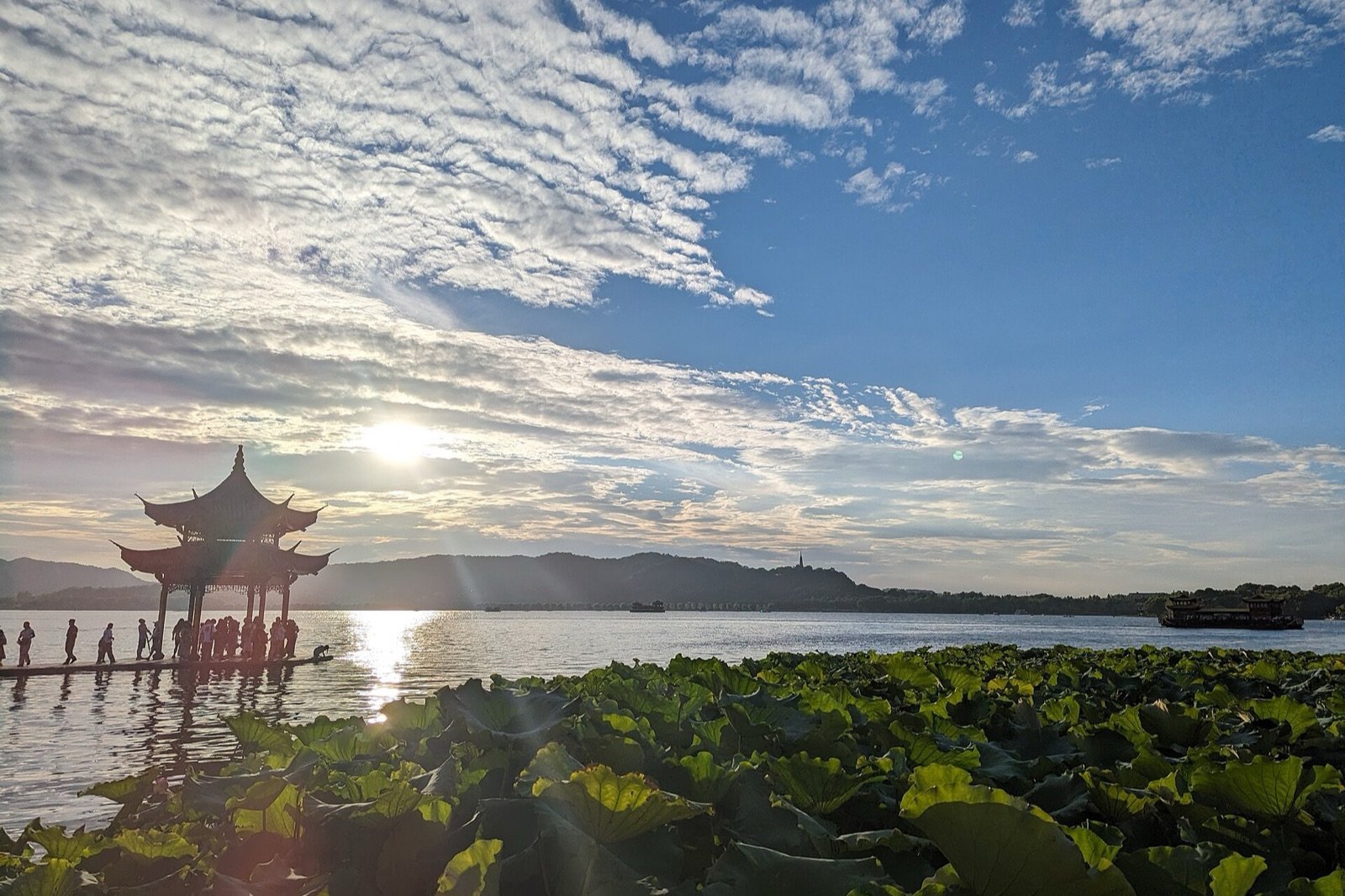 Jixian Pavilion and lotus leaves beside West Lake in Hangzhou at sunset.