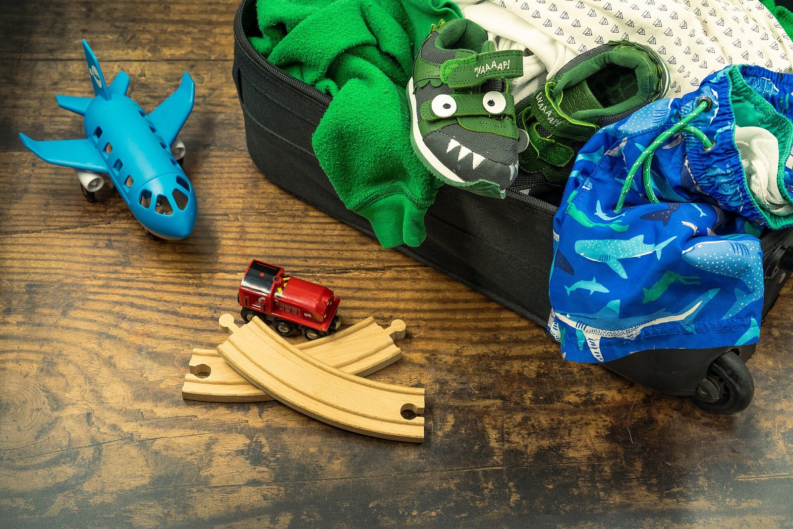 Children's clothing and shoes arranged in an open suitcase for a trip