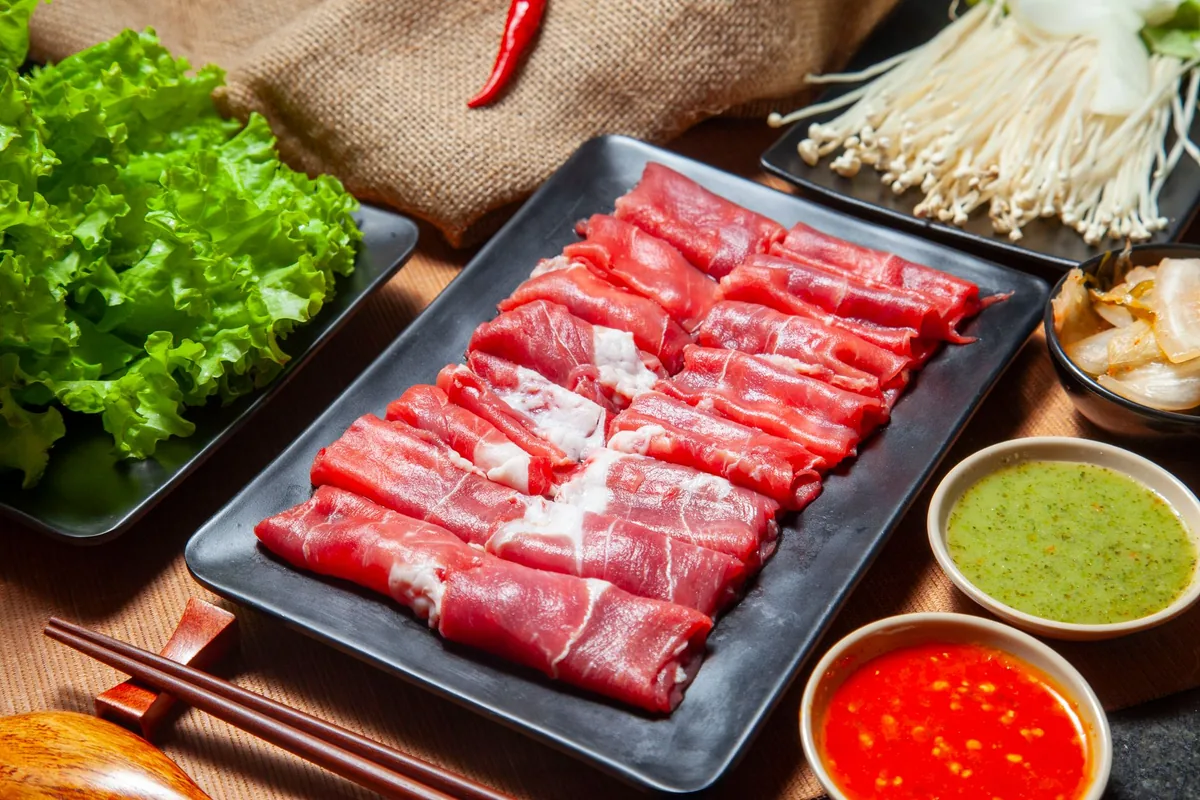 Thinly sliced beef, mushrooms and dipping sauces arranged for hot pot