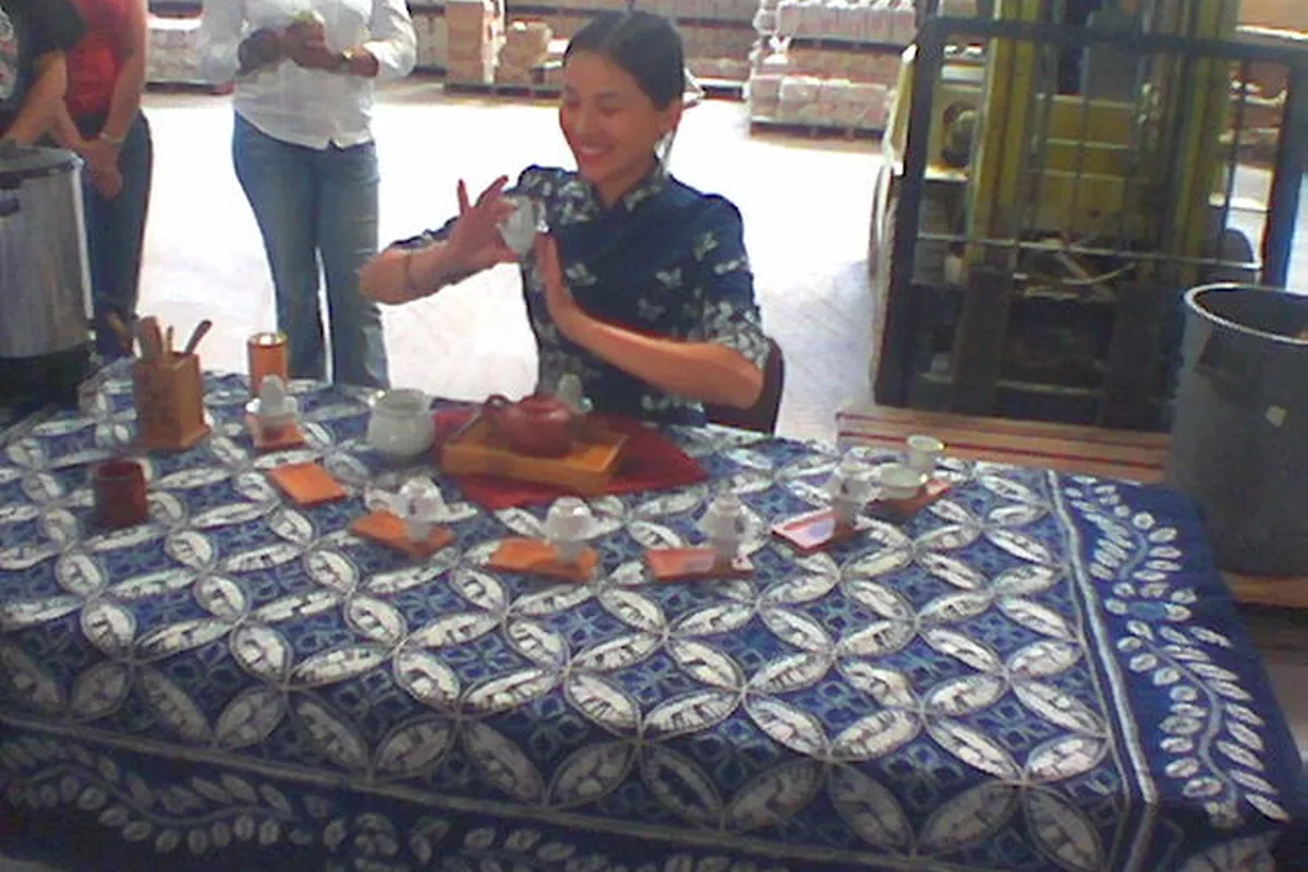 Host demonstrating Chinese tea preparation at a tea table