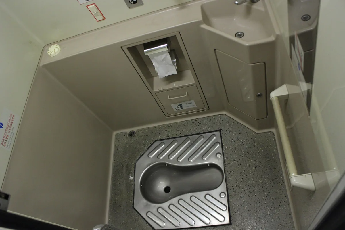 Squat toilet and paper dispenser inside a China Railways CRH2A train