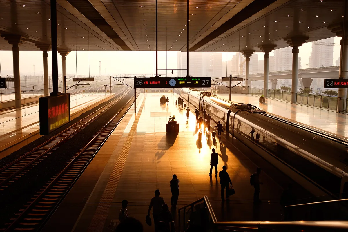High-speed train and passengers on a sunlit station platform