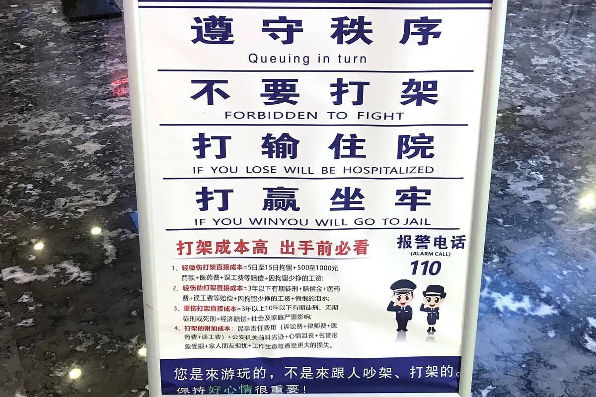 Public-order sign at a Guizhou attraction warning visitors not to fight and displaying police number 110