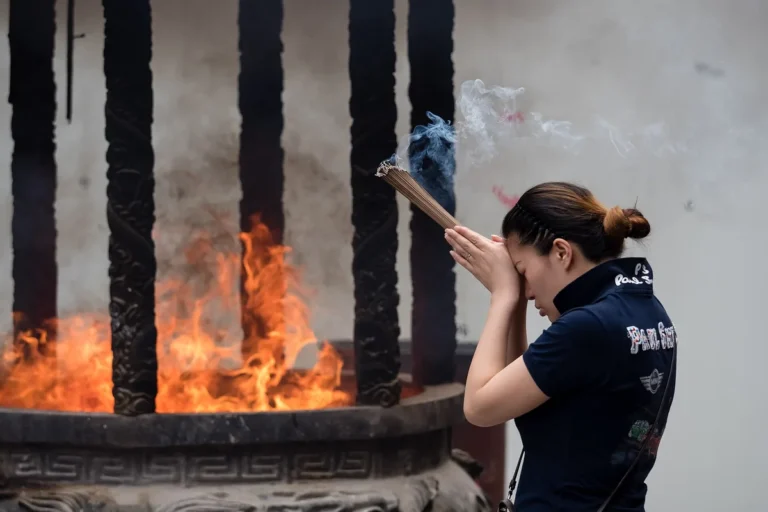 Visitor lighting incense in a courtyard at Shanghai Jade Buddha Temple