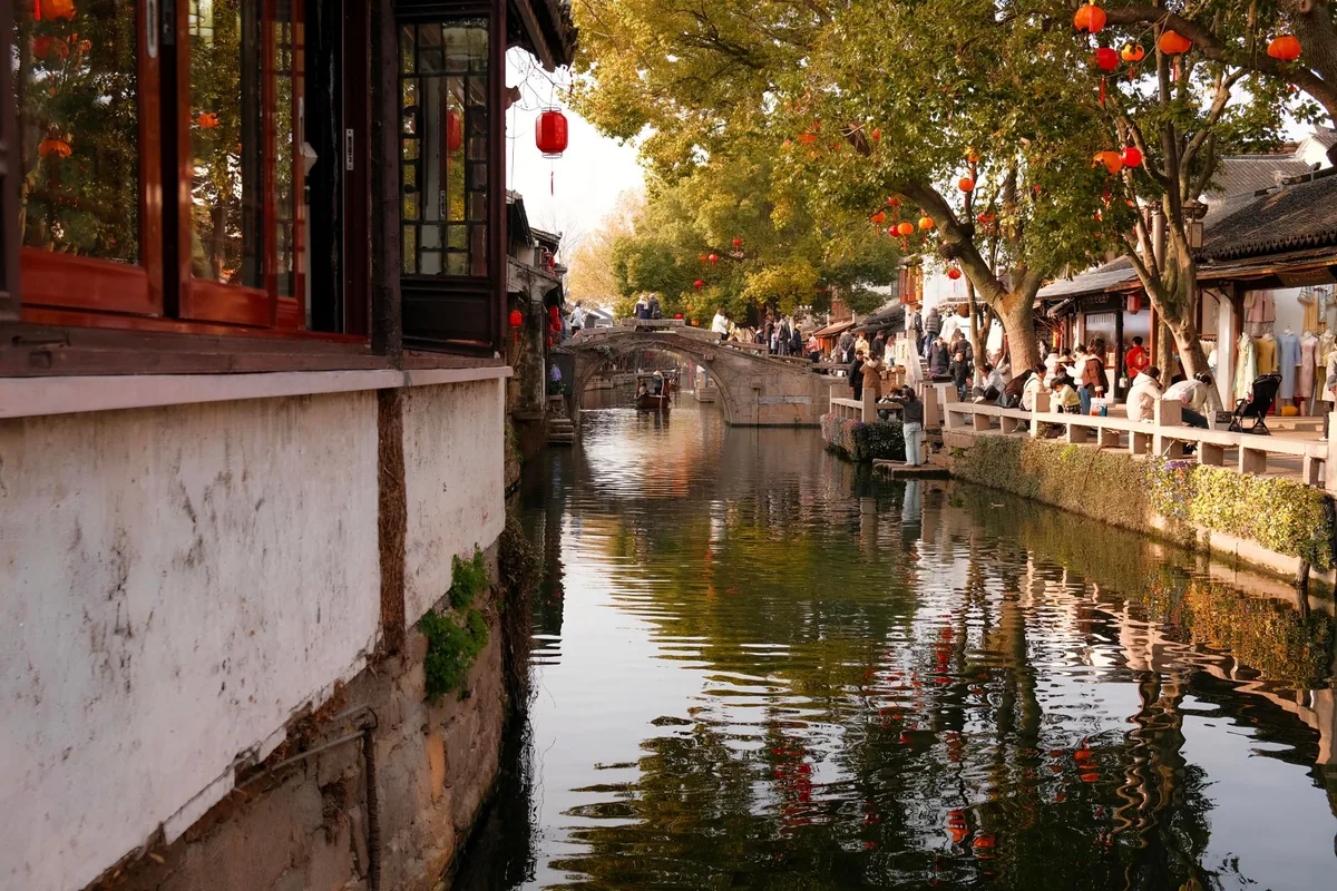 Historic Suzhou canal lined with red lanterns and stone bridges