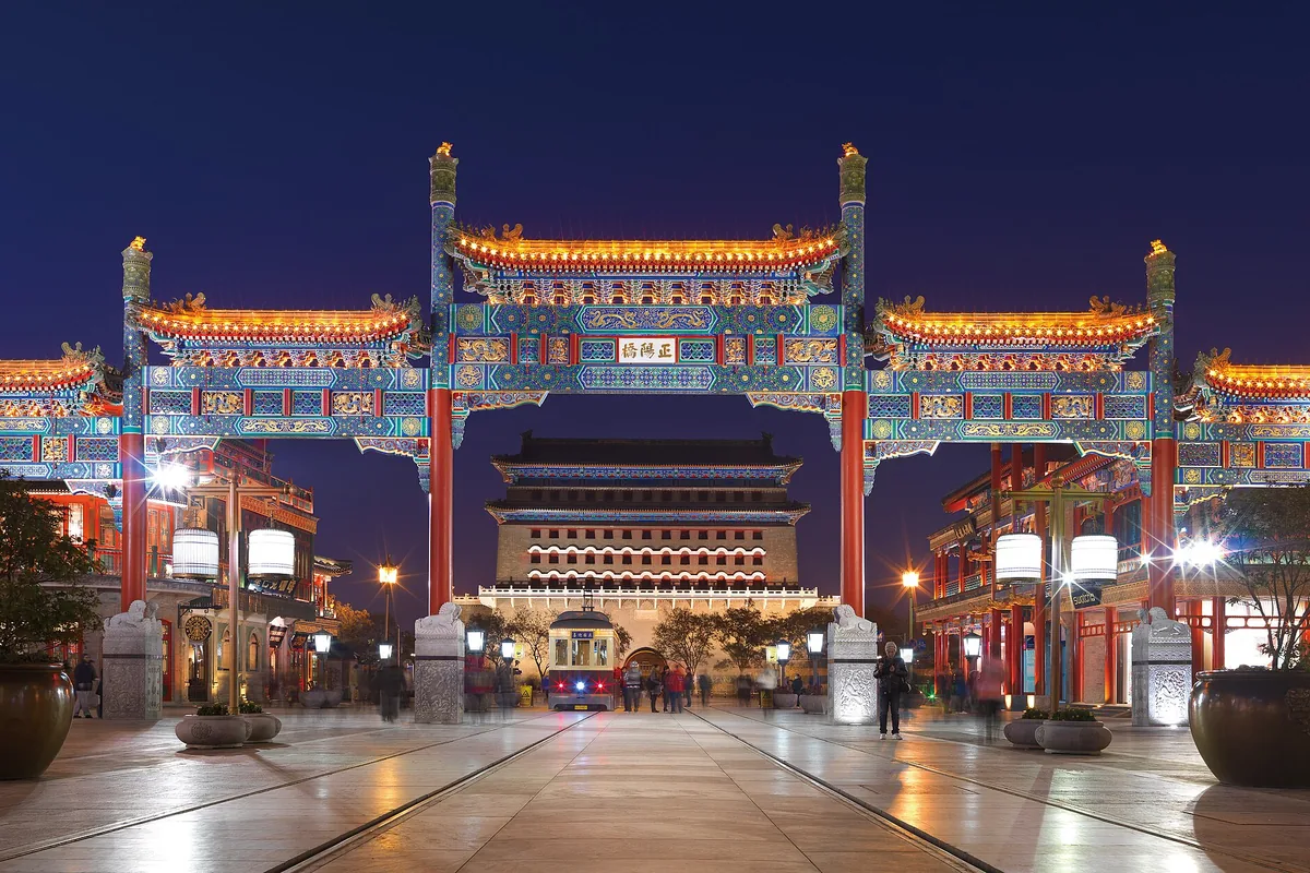 Illuminated Qianmen archway and tram tracks at night in Beijing