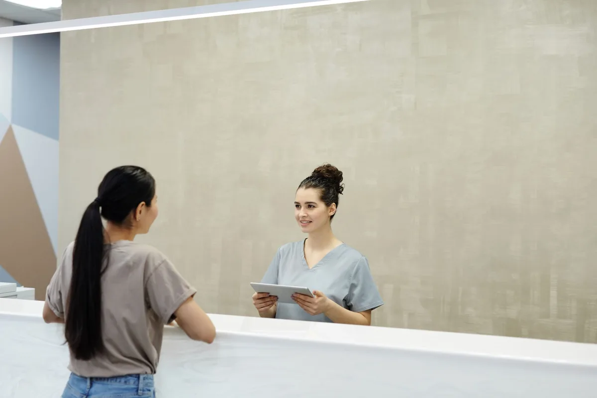 Patient speaking with a receptionist at a medical facility