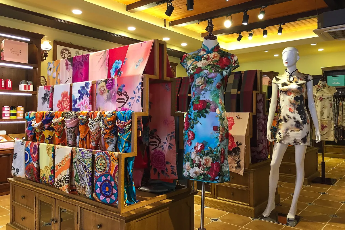 Qipao dresses and silk scarves displayed in a Hangzhou shop