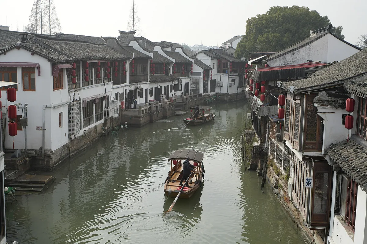 Canal boats passing traditional waterside buildings in Zhujiajiao